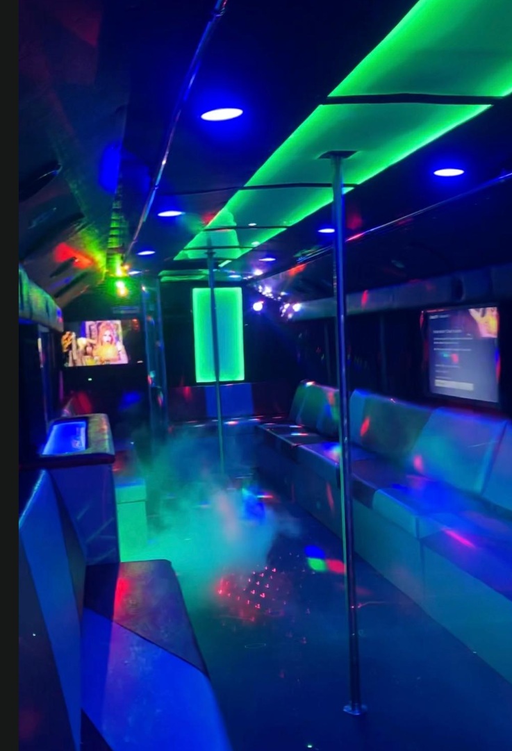 Interior con luces neón verdes y pole en el party bus